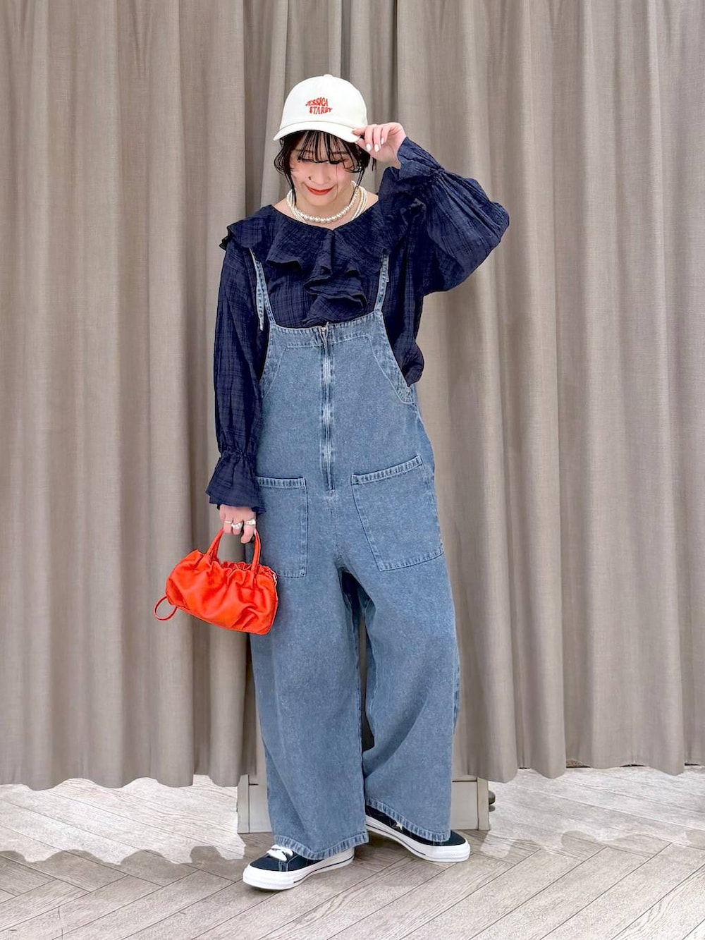 ブルー系のスニーカー、ブルー系のサロペット/オーバーオール、オレンジ系のショルダーバッグを着用したレディースの冬コーディネートの2枚目の写真