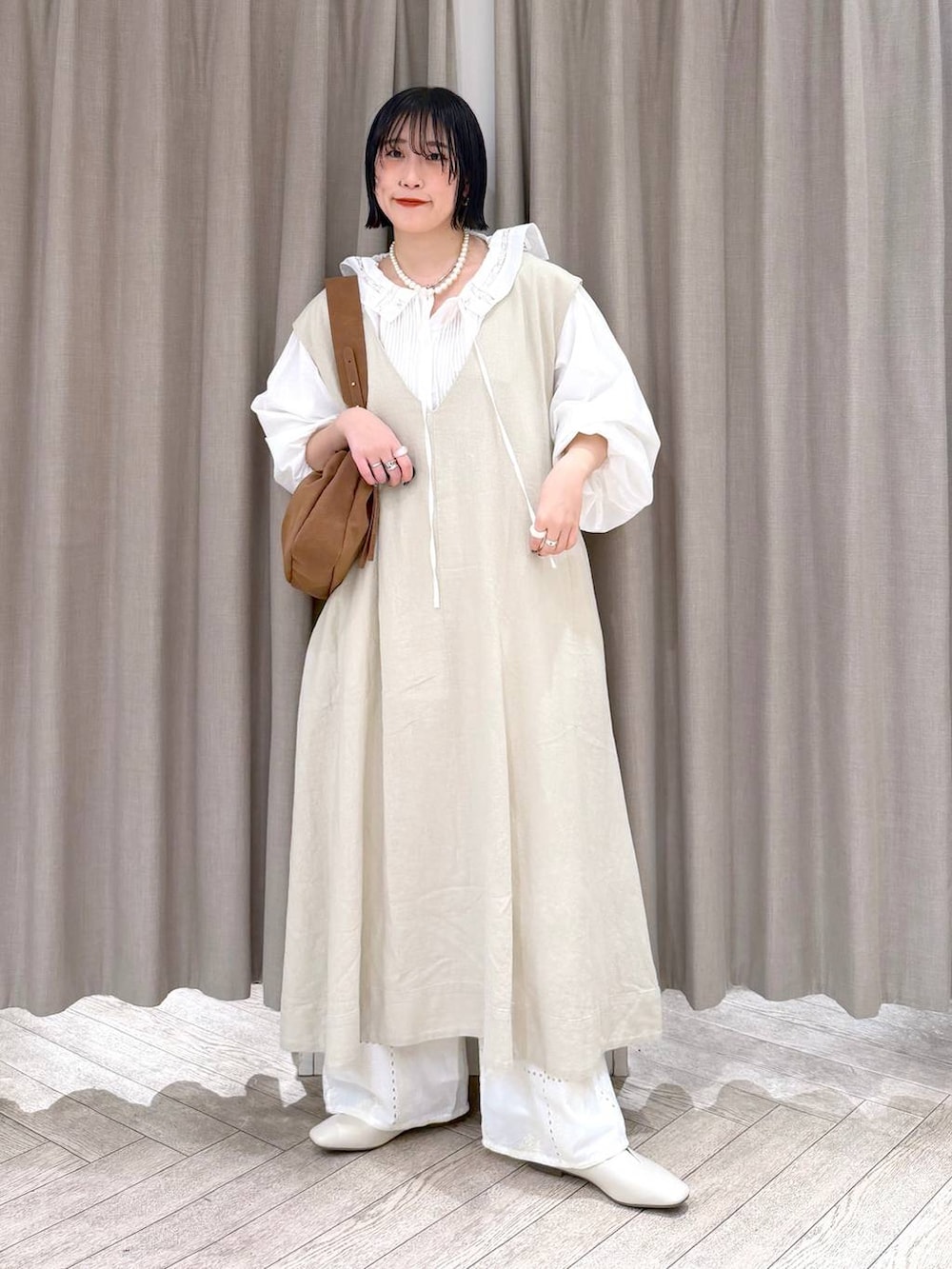 ベージュ系のジャンパースカート、ベージュ系のパンプス、ベージュ系のトートバッグを着用したレディースの冬コーディネートの10枚目の写真