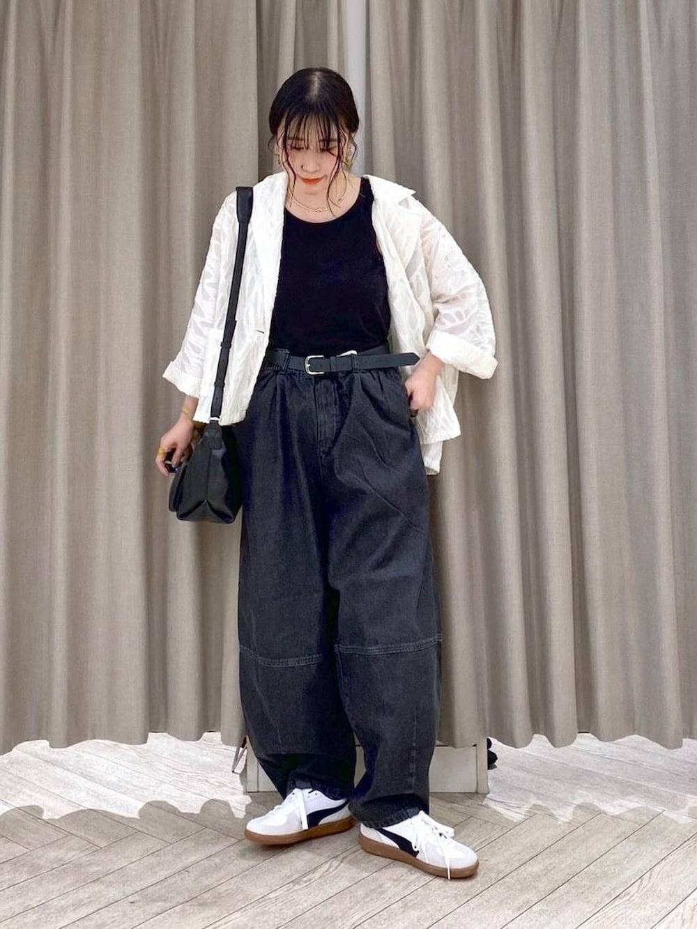 ブラック系のデニムパンツ、ホワイト系のスニーカー、ブラック系のショルダーバッグを着用したレディースの秋コーディネートの2枚目の写真