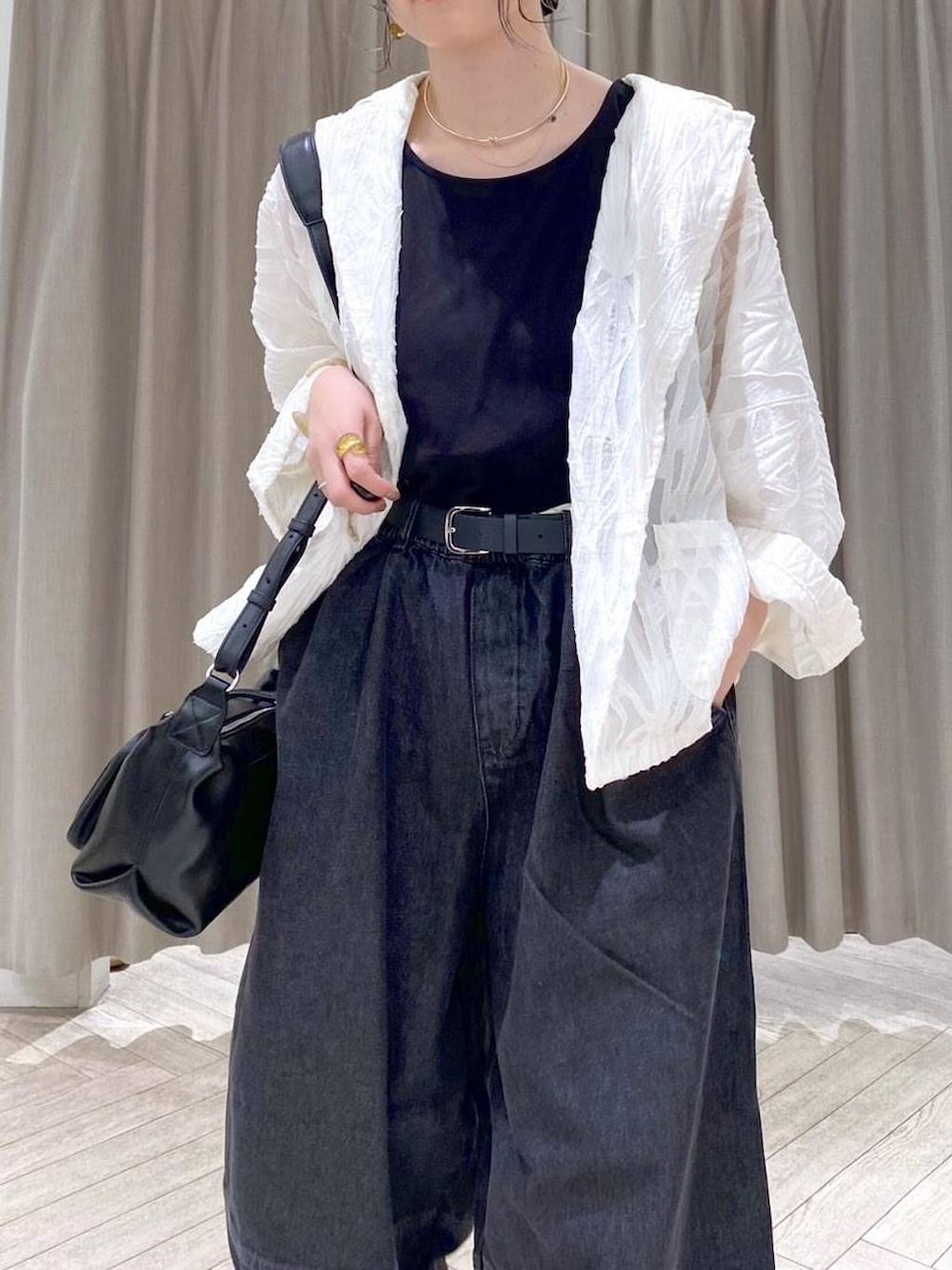 ブラック系のデニムパンツ、ホワイト系のスニーカー、ブラック系のショルダーバッグを着用したレディースの秋コーディネートの5枚目の写真