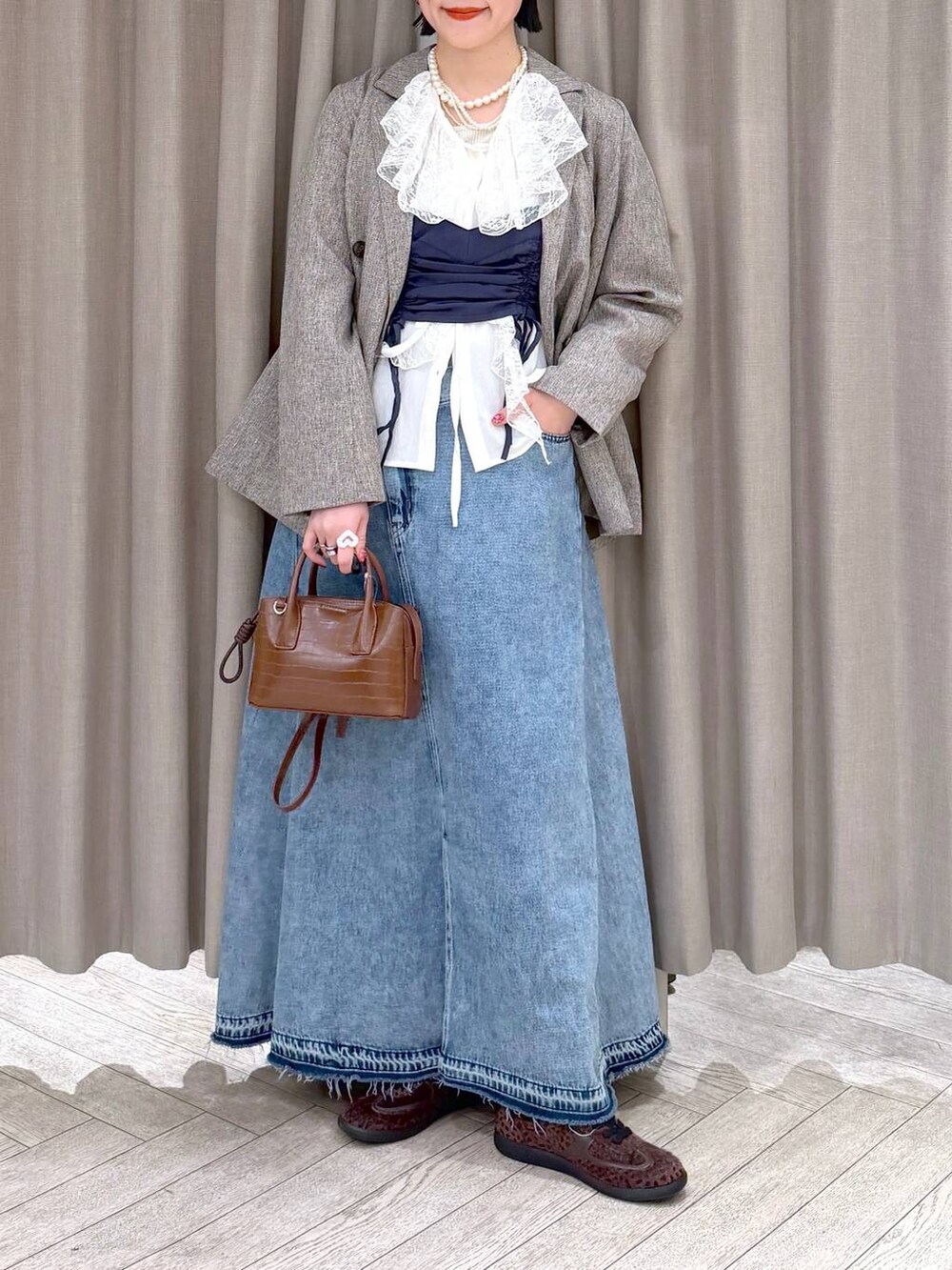 ベージュ系のテーラードジャケット、ブルー系のデニムスカート、ブラウン系のトートバッグを着用したレディースの冬コーディネートの7枚目の写真