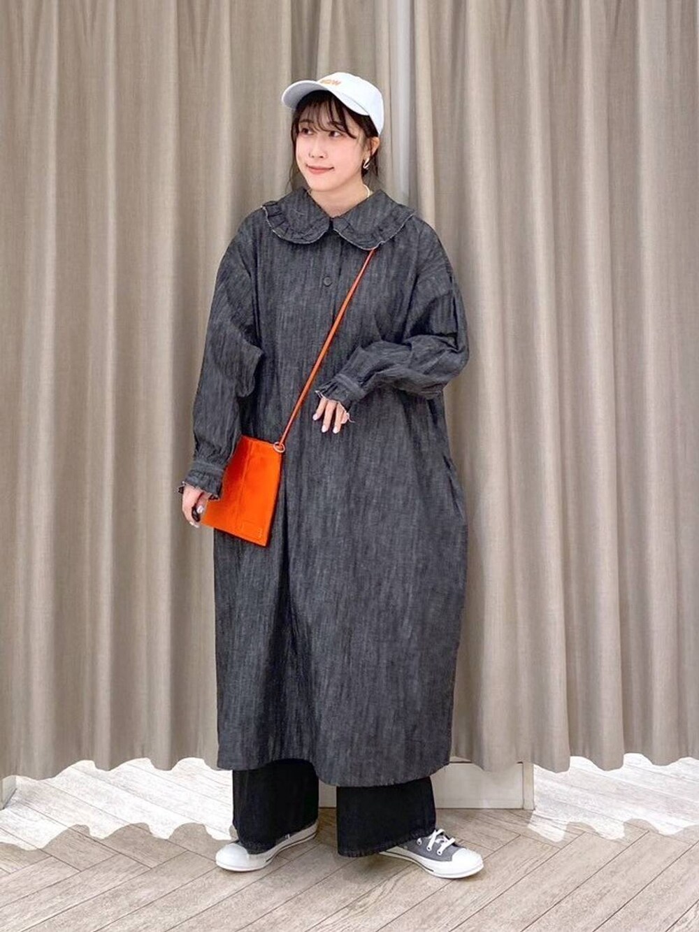 ブラック系のデニムパンツ、グレー系のスニーカー、オレンジ系のショルダーバッグを着用したレディースの秋コーディネートの7枚目の写真
