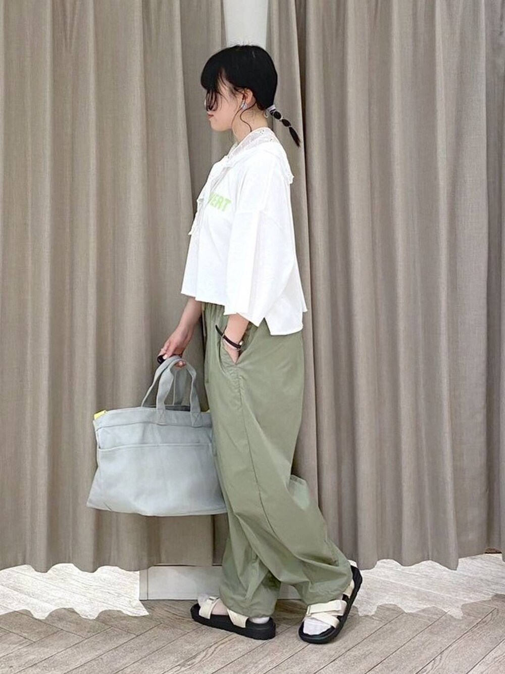 ベージュ系のサンダル、グリーン系のTシャツ/カットソー、グレー系のトートバッグを着用したレディースの夏コーディネートの2枚目の写真