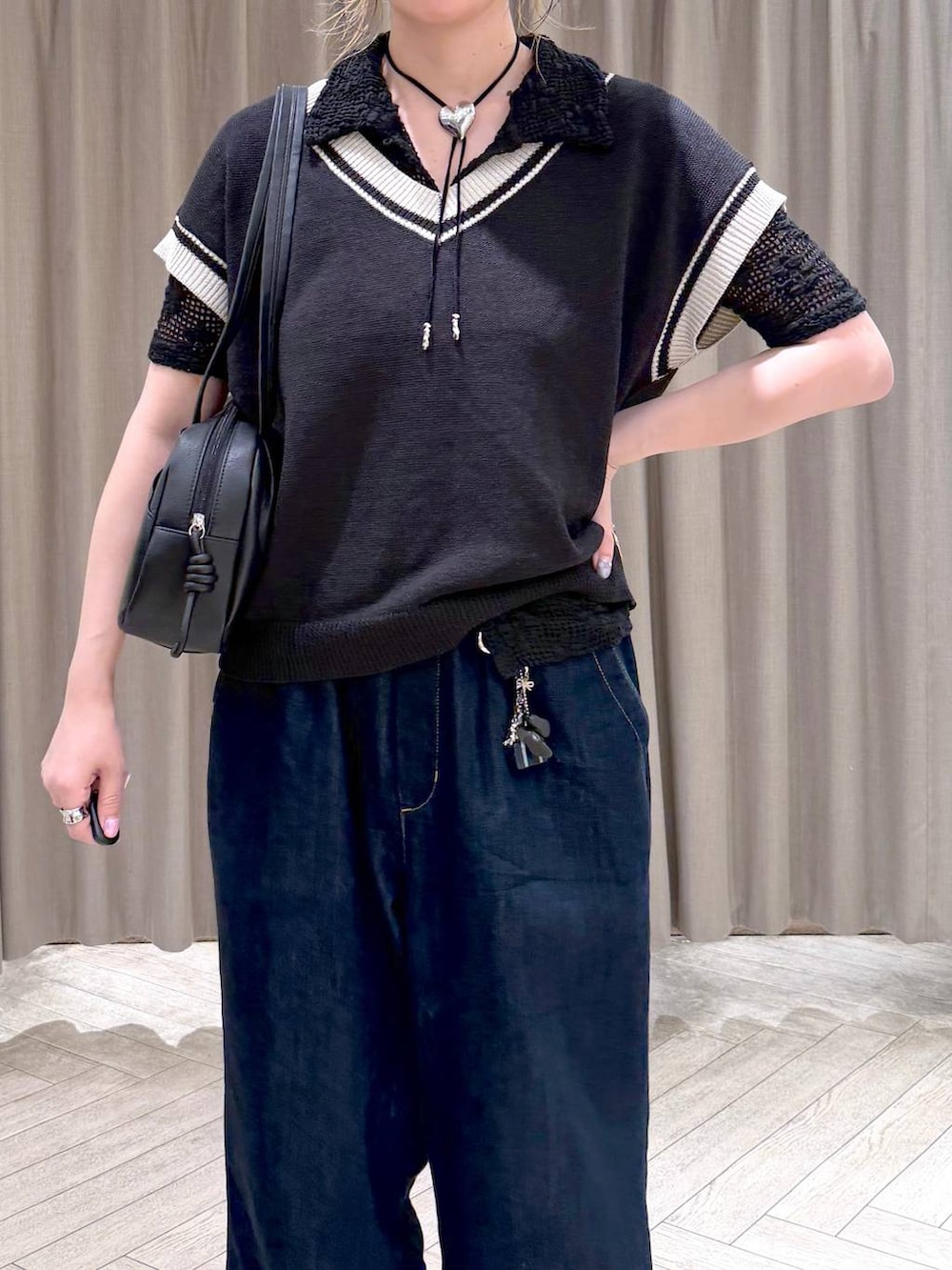 ブラック系のショルダーバッグ、ブラック系のニット/セーター、ブルー系のデニムパンツを着用したレディースの夏コーディネートの5枚目の写真