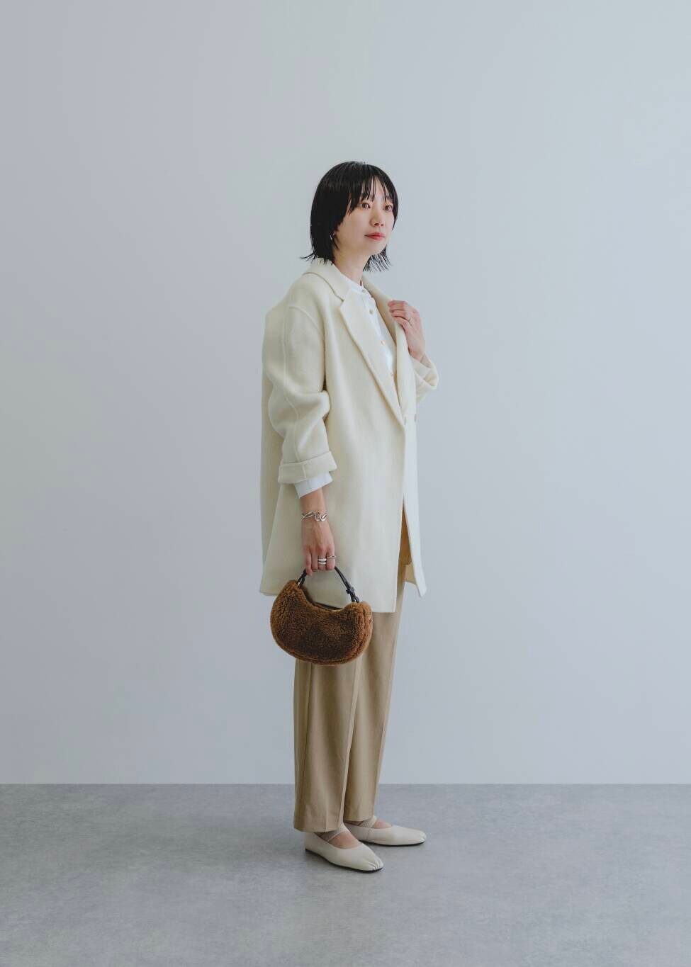 イエロー系のその他パンツ、ホワイト系のシャツ/ブラウス、ホワイト系のチェスターコートを着用したレディースの秋コーディネートの2枚目の写真