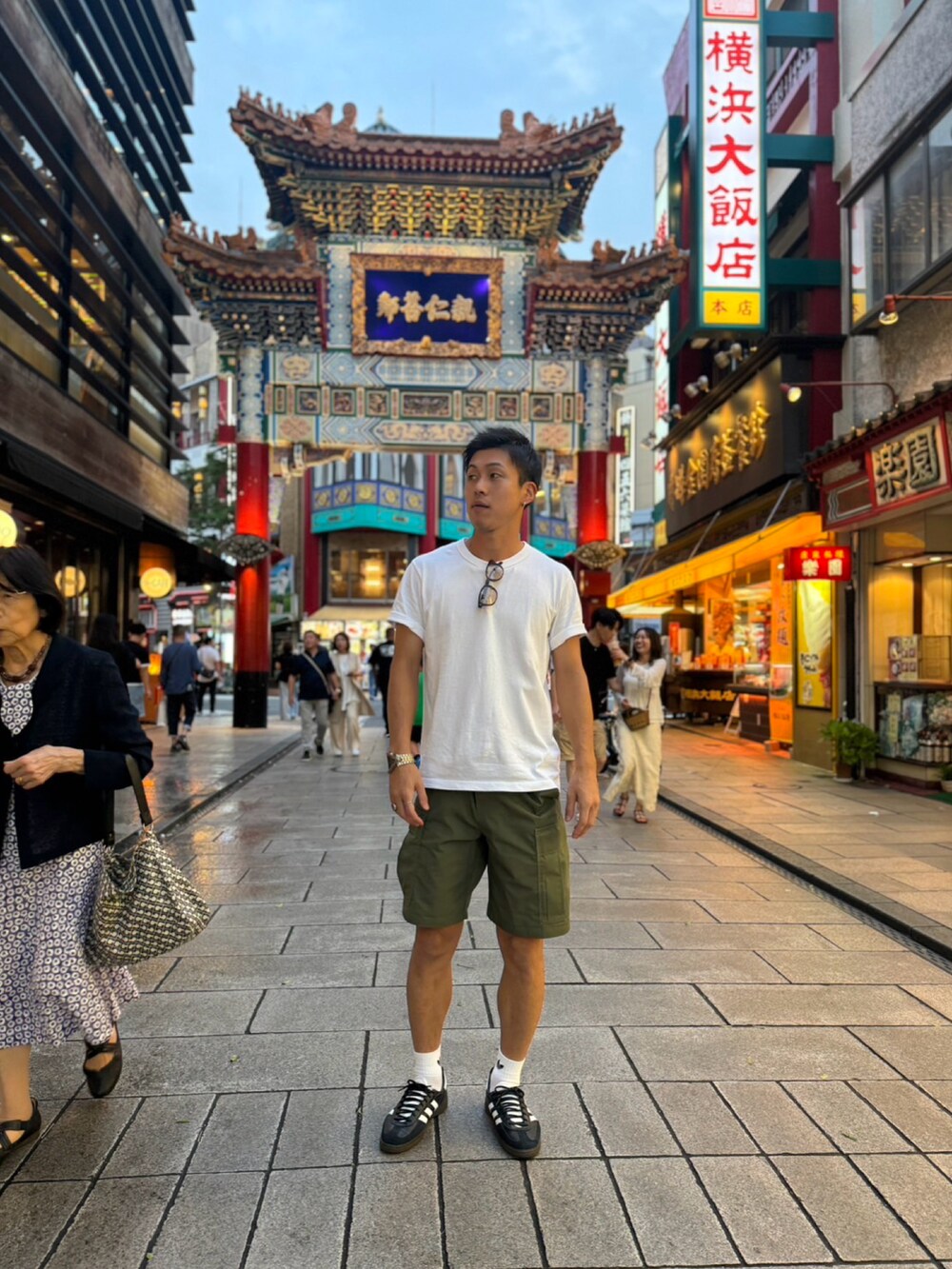 ホワイト系のTシャツ/カットソー、グリーン系のカーゴパンツ、ブラック系のスニーカーを着用したメンズの夏コーディネートの3枚目の写真