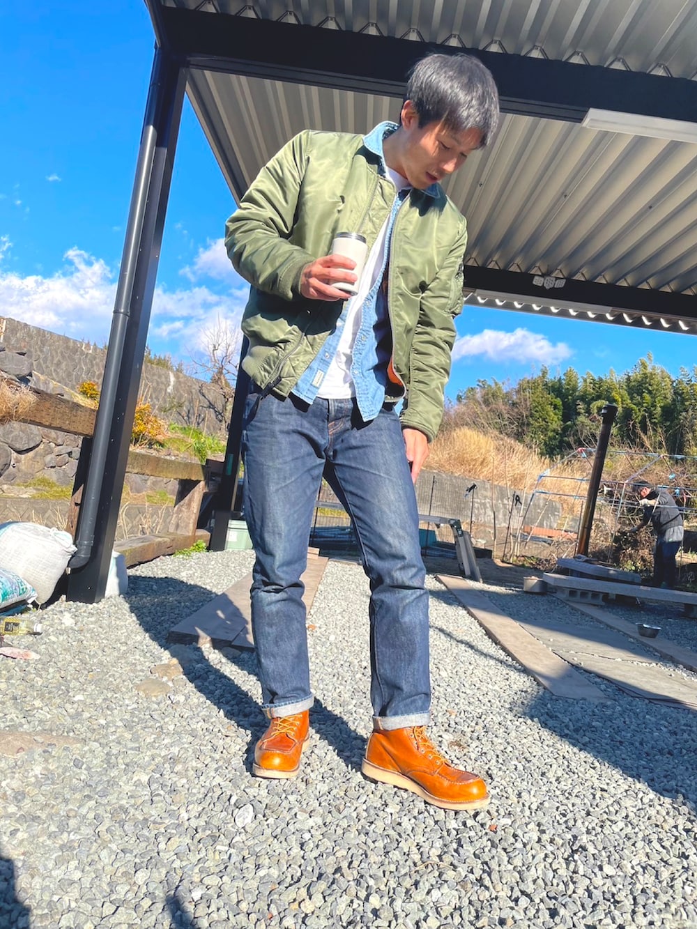 グリーン系のMA-1、ブルー系のシャツ/ブラウス、ブルー系のデニムパンツを着用したメンズの冬コーディネートの2枚目の写真