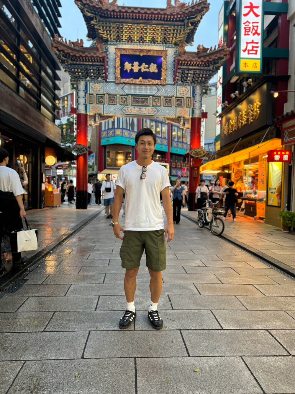 ホワイト系のTシャツ/カットソー、グリーン系のカーゴパンツ、ブラック系のスニーカーを着用したメンズの夏コーディネートの2枚目の写真