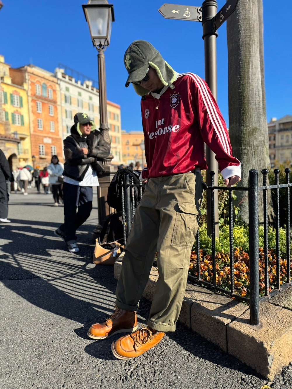 レッド系のジャージ、グリーン系のカーゴパンツ、ブラウン系のブーツを着用したメンズの冬コーディネートの2枚目の写真