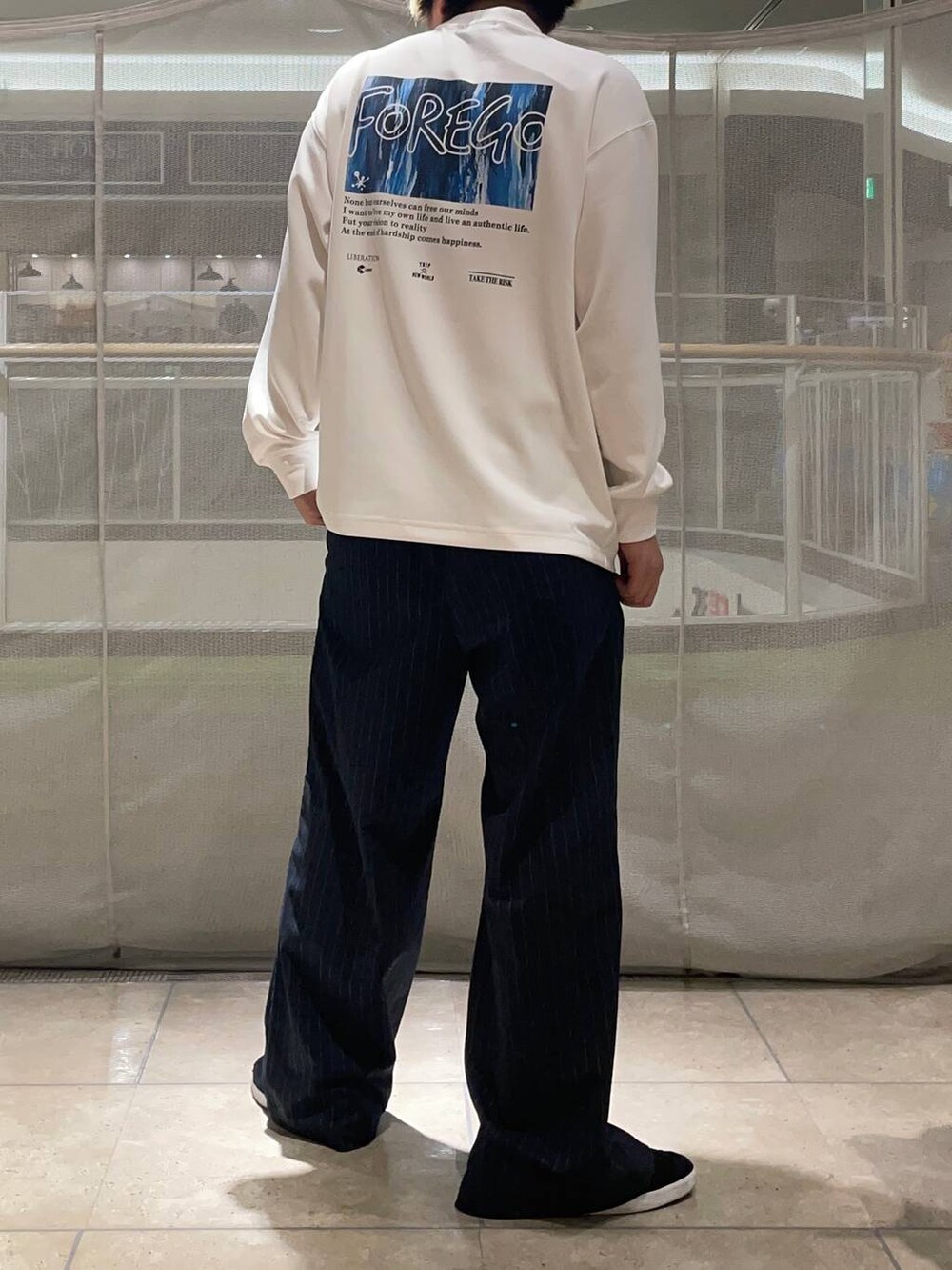 ブルー系のスラックス、ブラック系のスニーカー、ホワイト系のTシャツ/カットソーを着用したメンズの秋コーディネートの4枚目の写真