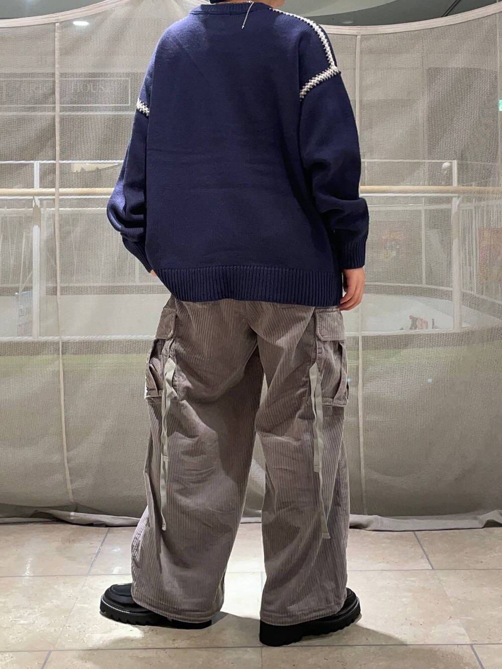 グレー系のカーゴパンツ、ブラック系のドレスシューズ、ブルー系のニット/セーターを着用したメンズの秋コーディネートの3枚目の写真