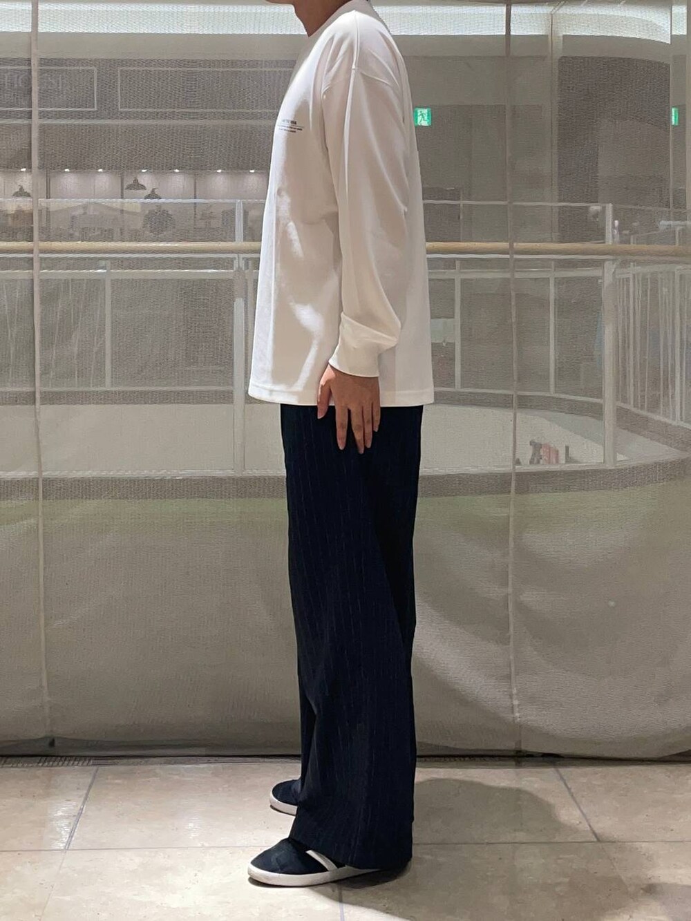 ブルー系のスラックス、ブラック系のスニーカー、ホワイト系のTシャツ/カットソーを着用したメンズの秋コーディネートの3枚目の写真