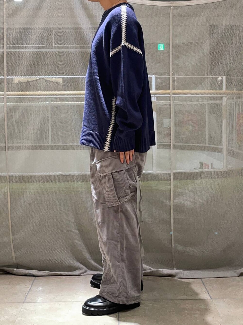 グレー系のカーゴパンツ、ブラック系のドレスシューズ、ブルー系のニット/セーターを着用したメンズの秋コーディネートの2枚目の写真