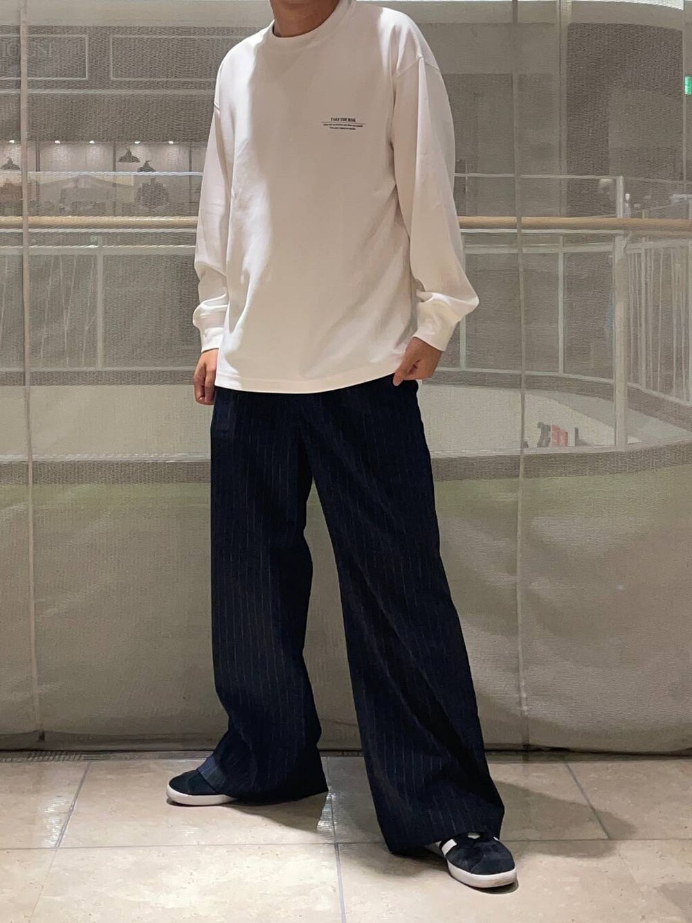 ブルー系のスラックス、ブラック系のスニーカー、ホワイト系のTシャツ/カットソーを着用したメンズの秋コーディネートの2枚目の写真