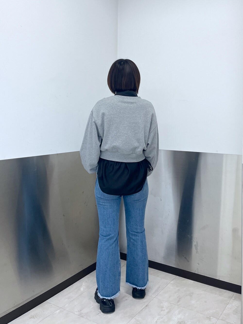 グレー系のスウェット、ブルー系のデニムパンツ、ホワイト系のショルダーバッグを着用したレディースの冬コーディネートの3枚目の写真