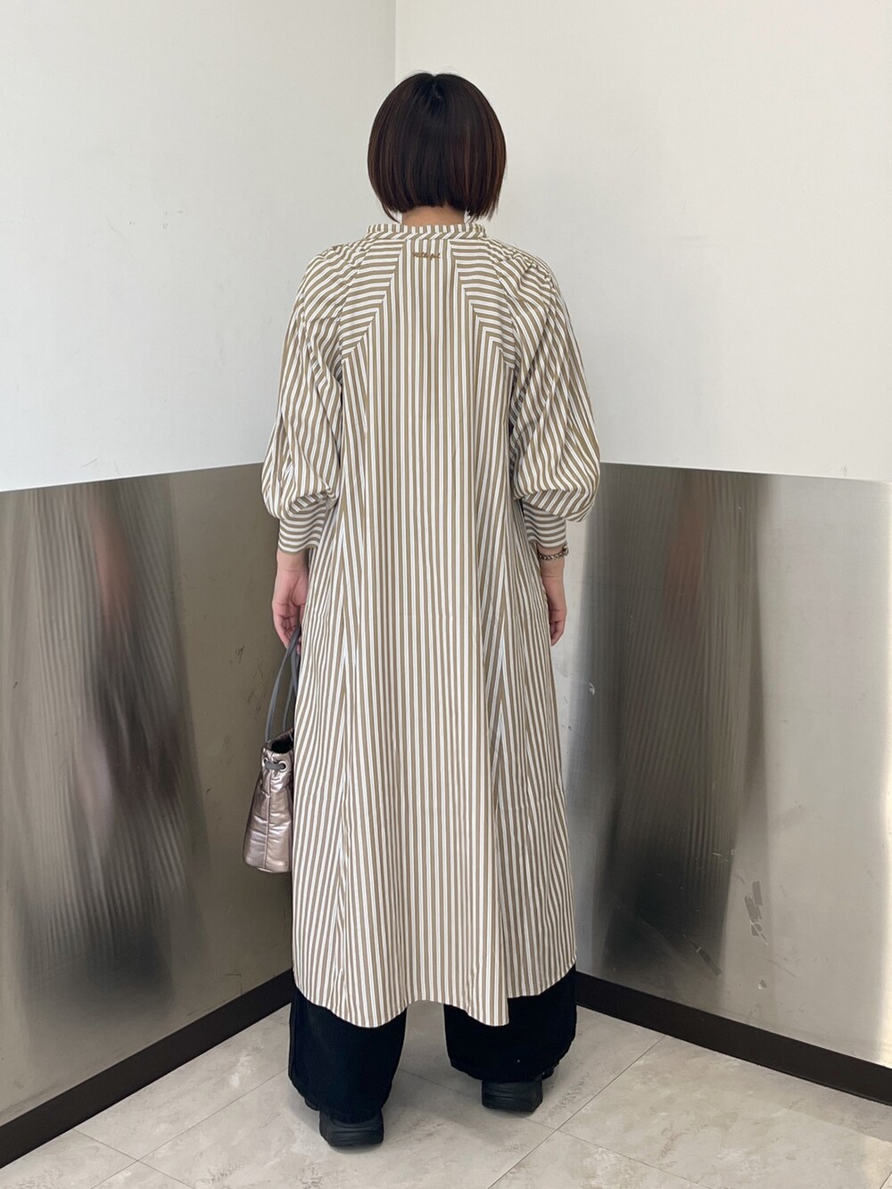 ブラック系のデニムパンツ、ベージュ系のパーカー、ベージュ系のシャツワンピースを着用したレディースの冬コーディネートの5枚目の写真