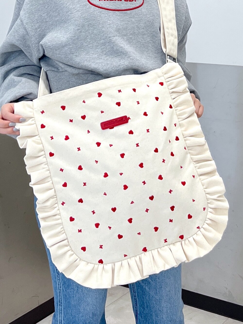 グレー系のスウェット、ブルー系のデニムパンツ、ホワイト系のショルダーバッグを着用したレディースの冬コーディネートの5枚目の写真