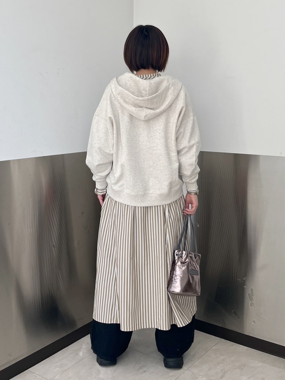 ブラック系のデニムパンツ、ベージュ系のパーカー、ベージュ系のシャツワンピースを着用したレディースの冬コーディネートの2枚目の写真