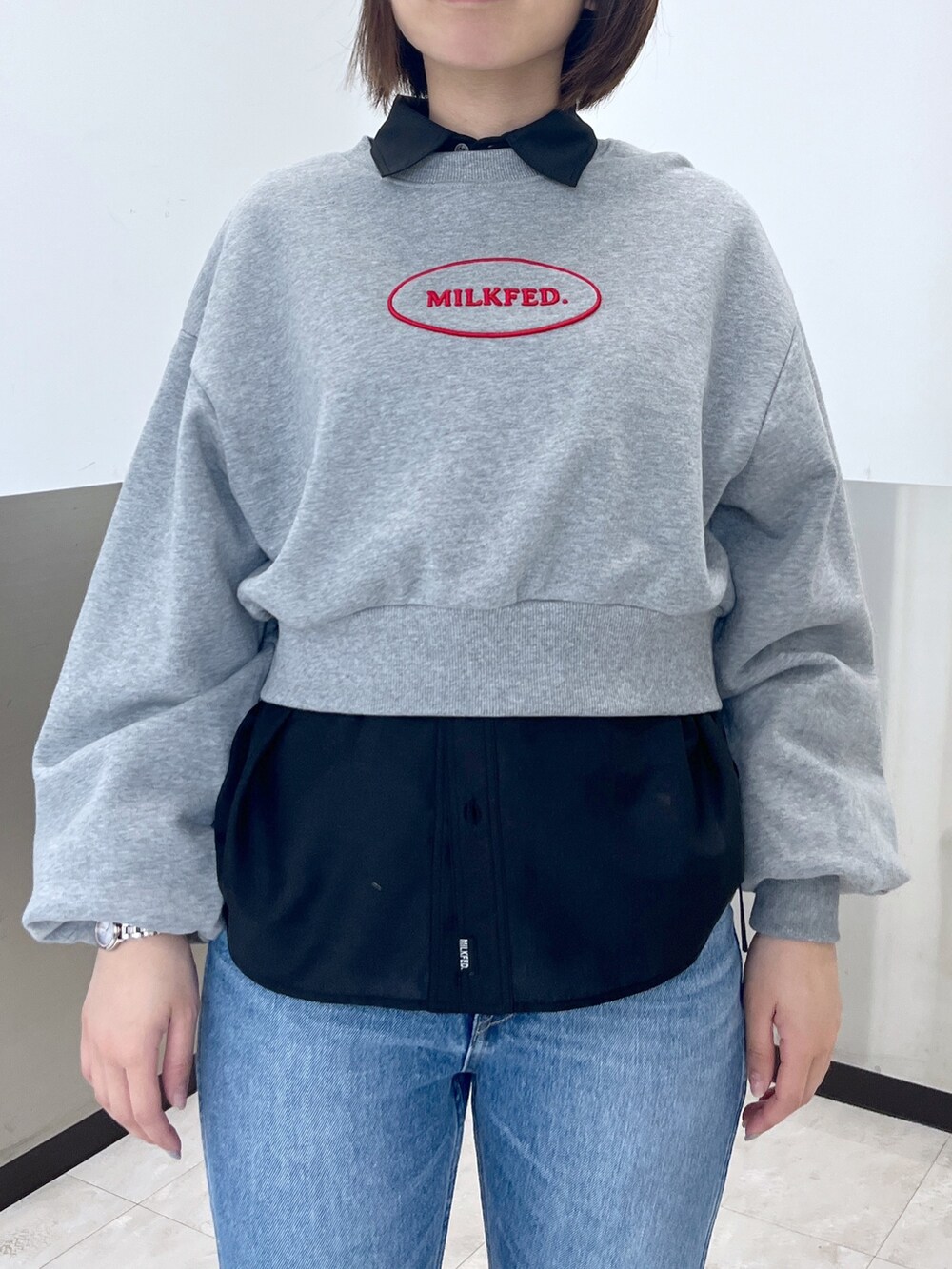 グレー系のスウェット、ブルー系のデニムパンツ、ホワイト系のショルダーバッグを着用したレディースの冬コーディネートの4枚目の写真