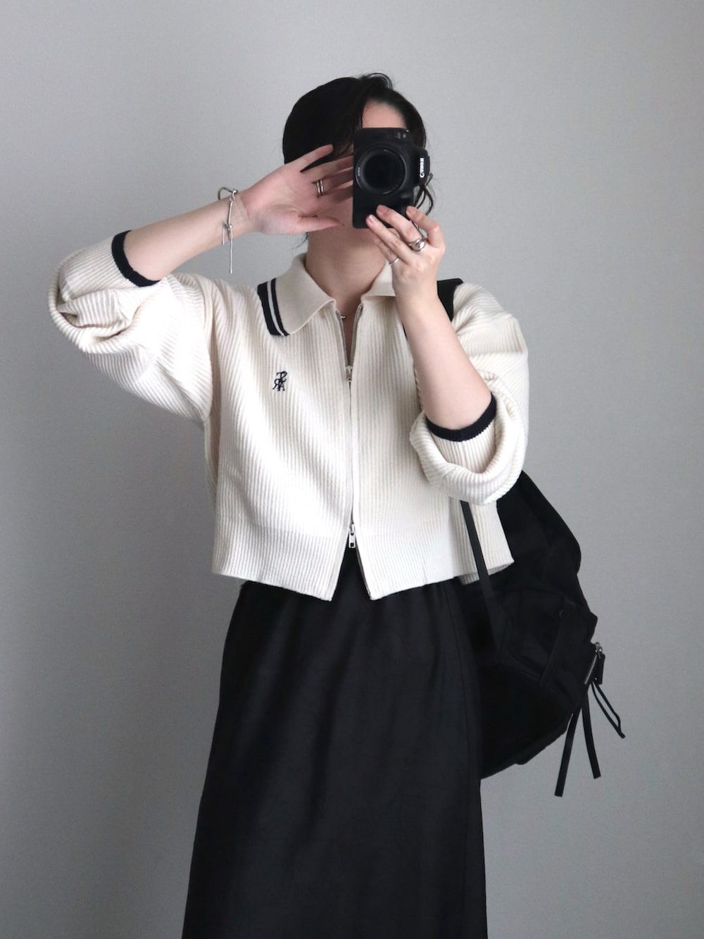 ホワイト系のニット/セーター、ブラック系のスカート、ブラック系のバックパック/リュックを着用したレディースの秋コーディネートの4枚目の写真