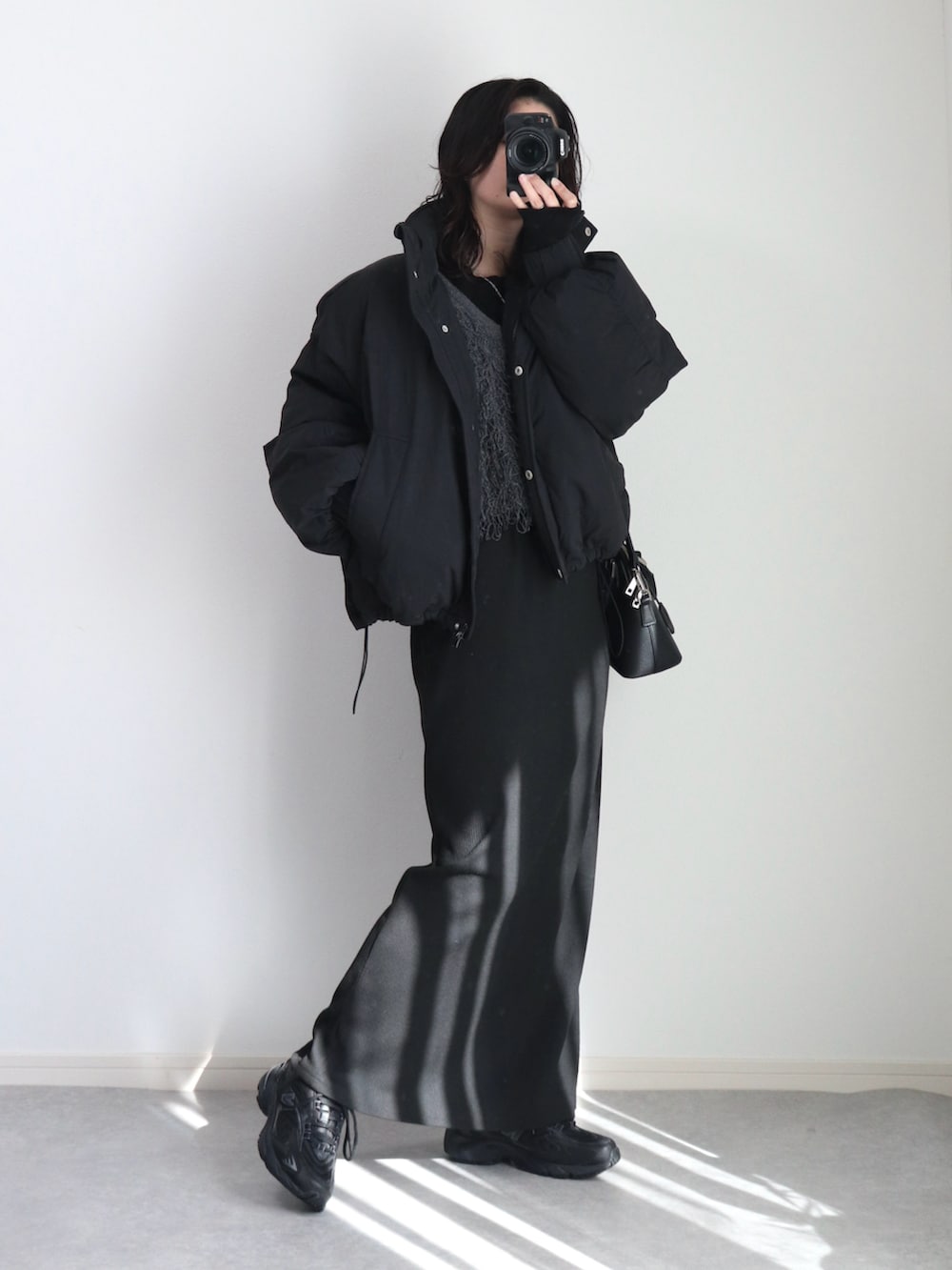 ブラック系のダウンジャケット/コート、グレー系のベスト、ブラック系のニット/セーターを着用したレディースの冬コーディネートの3枚目の写真