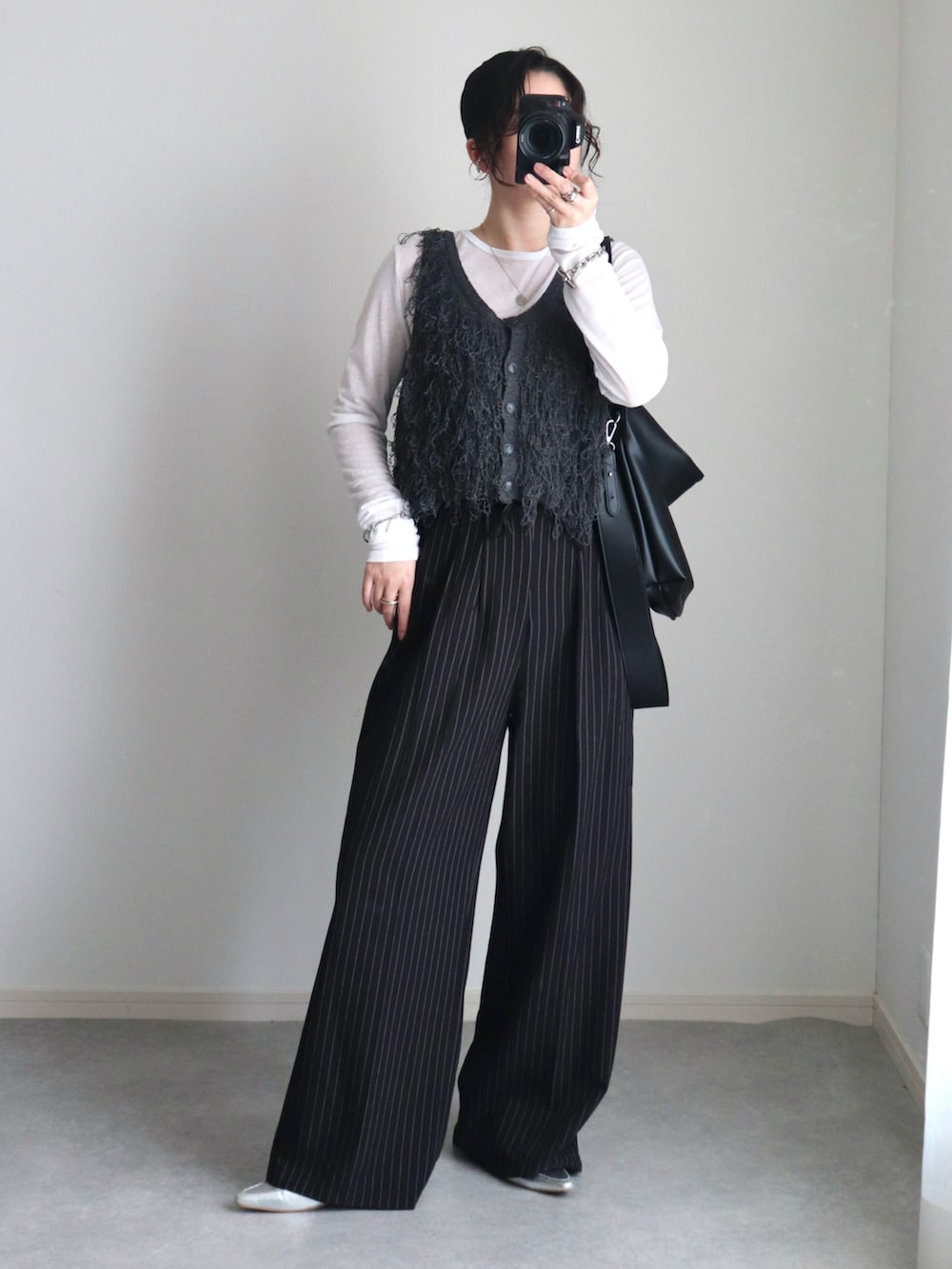 グレー系のベスト、ブラック系のスラックス、ブラック系のショルダーバッグを着用したレディースの秋コーディネートの2枚目の写真