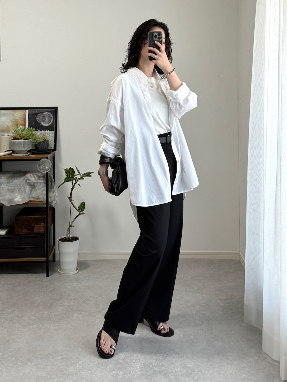 ブラック系のスラックス、ブラック系のサンダル、ブラック系のハンドバッグを着用したレディースの春コーディネートの2枚目の写真