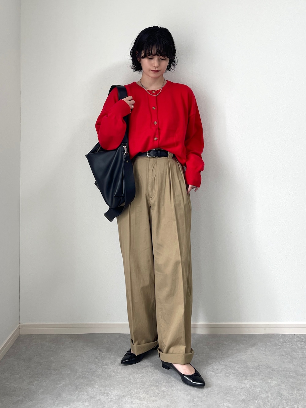 レッド系のカーディガン/ボレロ、ブラック系のショルダーバッグ、ベージュ系のチノパンツを着用したレディースの秋コーディネートの2枚目の写真
