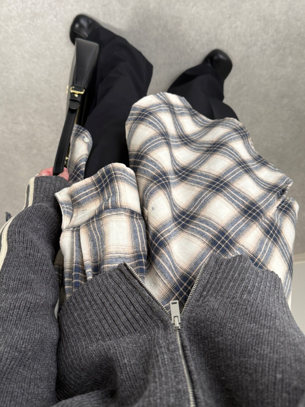 グレー系のニット/セーター、ホワイト系のシャツ/ブラウス、ブラック系のハンドバッグを着用したレディースの秋コーディネートの4枚目の写真