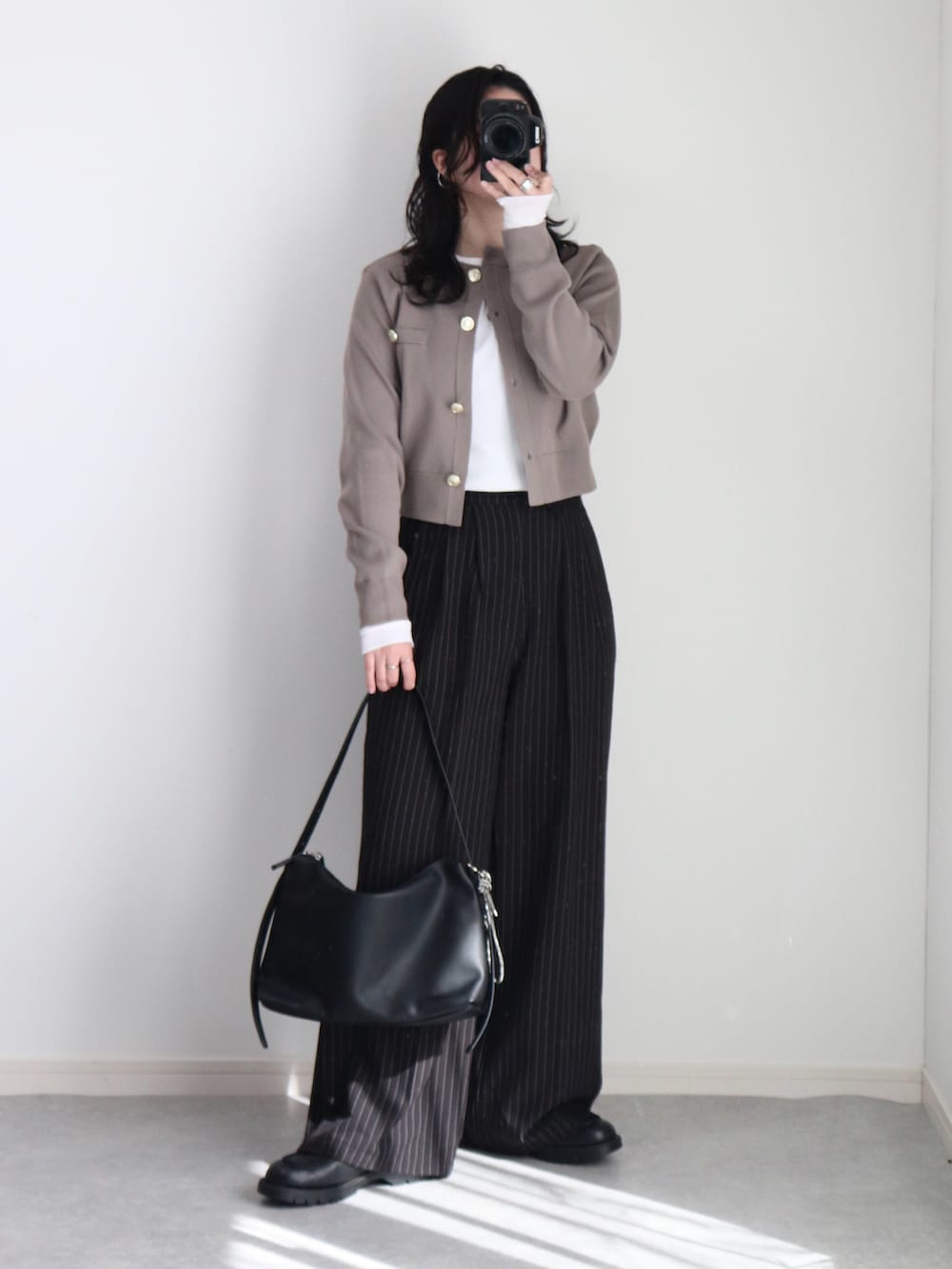 ブラック系のショルダーバッグ、ホワイト系のTシャツ/カットソー、ベージュ系のカーディガン/ボレロを着用したレディースの冬コーディネートの2枚目の写真