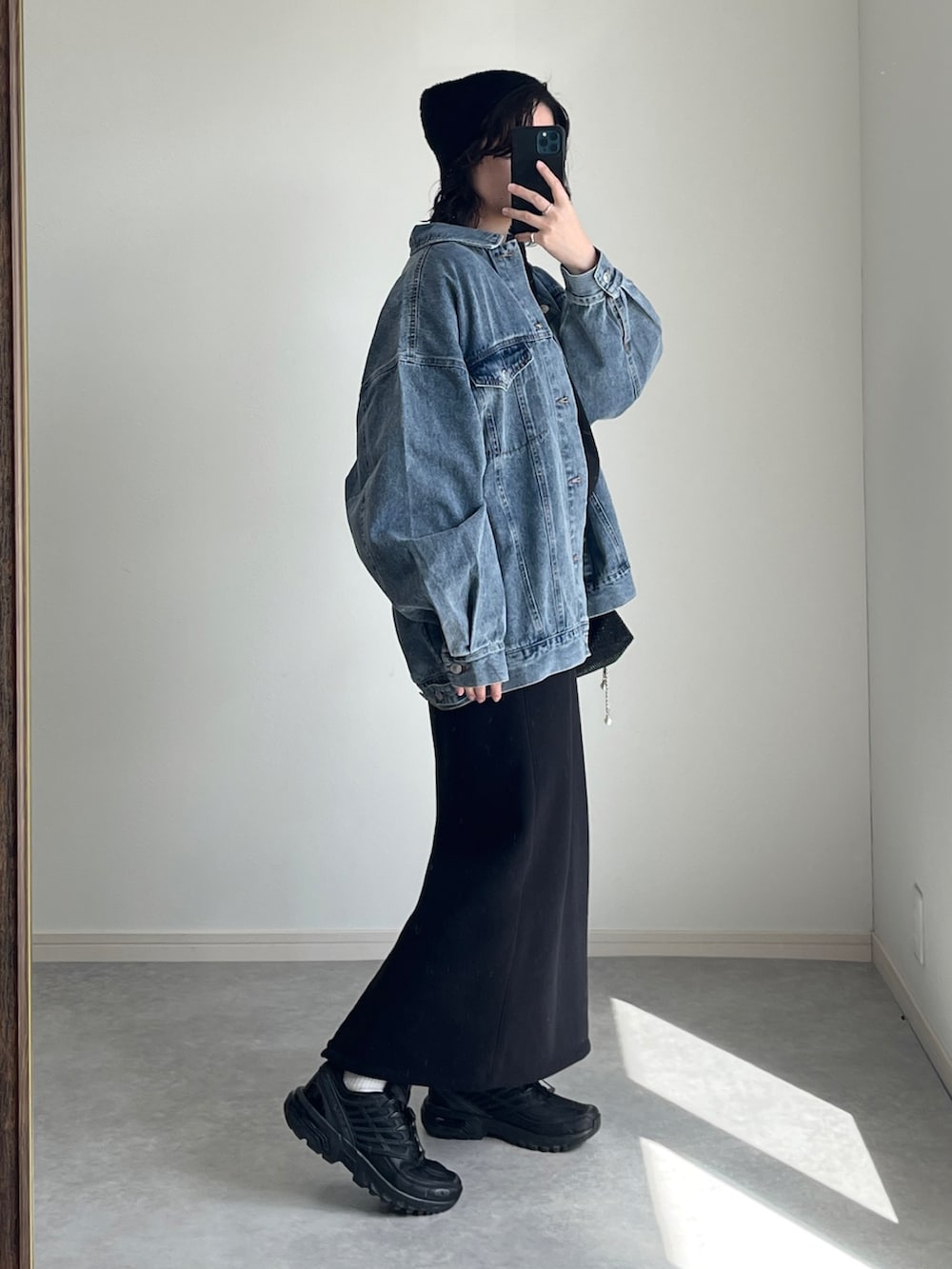 ブラック系のショルダーバッグ、ブラック系のニット/セーター、ブルー系のデニムジャケットを着用したレディースの冬コーディネートの3枚目の写真