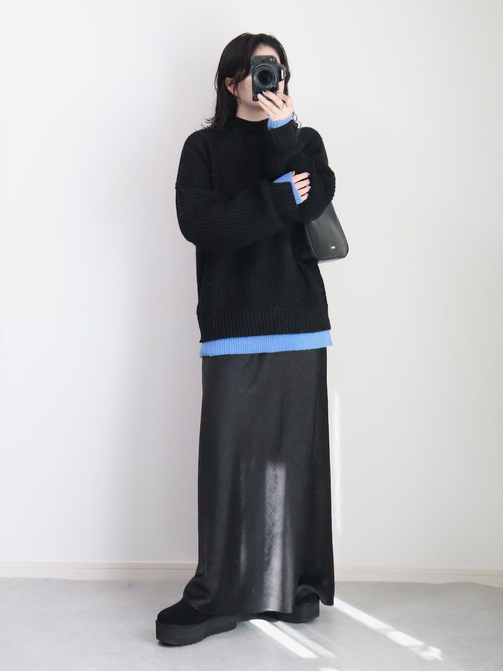 ブラック系のニット/セーター、ブラック系のスカート、ブラック系のハンドバッグを着用したレディースの冬コーディネートの2枚目の写真