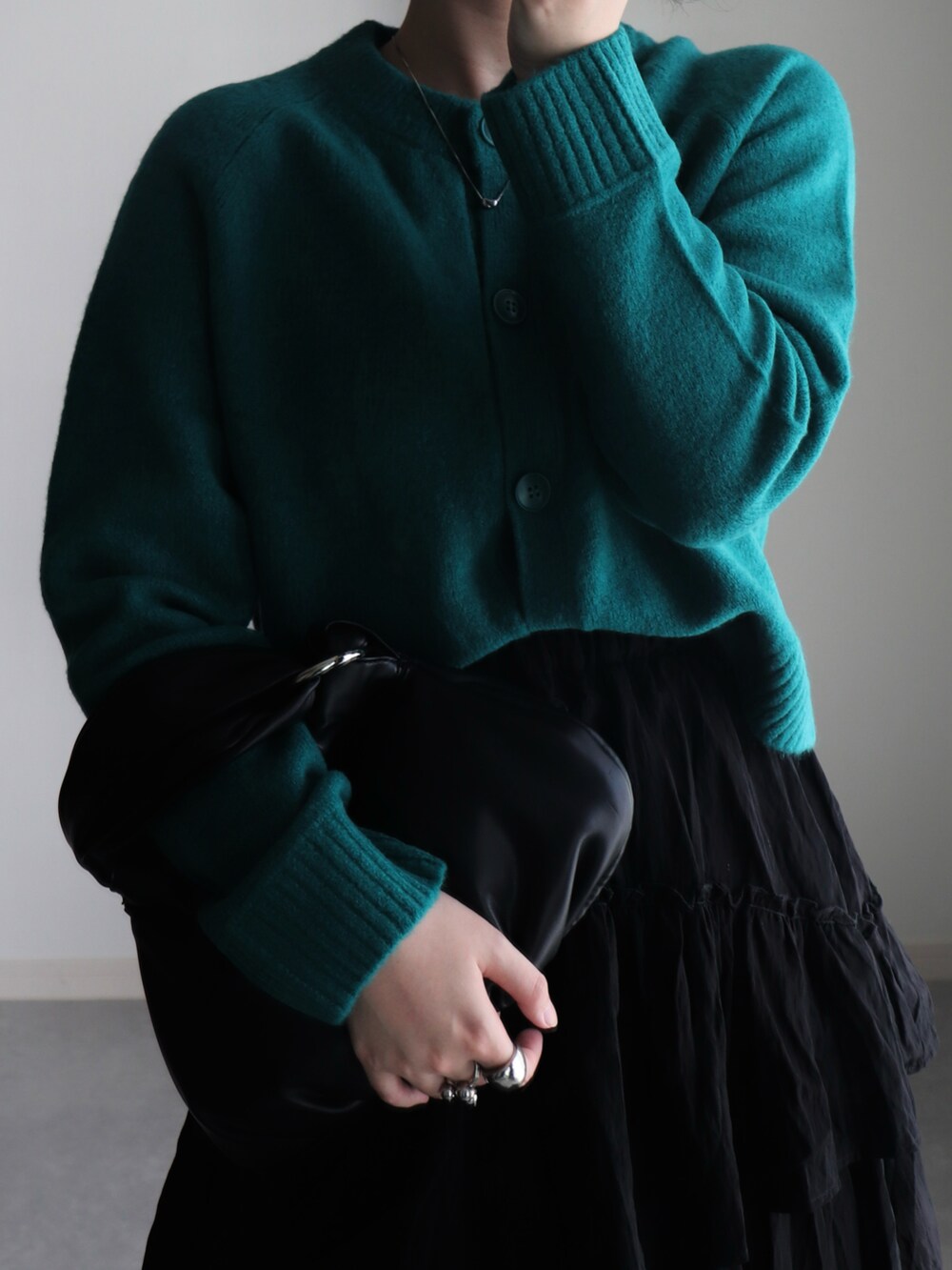 ブラック系のスカート、グリーン系のカーディガン/ボレロ、ブラック系のハンドバッグを着用したレディースの秋コーディネートの4枚目の写真