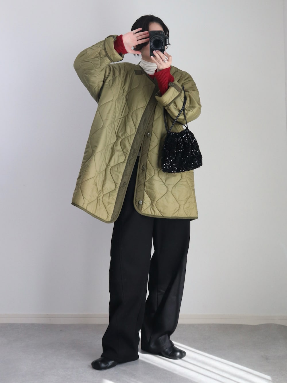 ブラック系のスウェットパンツ、ブラック系のブーツ、グリーン系のモッズコートを着用したレディースの秋コーディネートの3枚目の写真