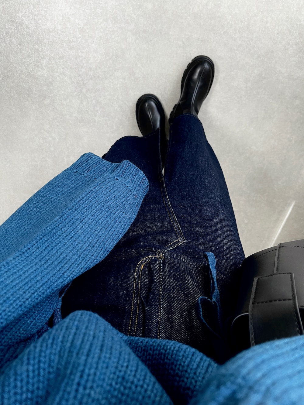 ブルー系のニット/セーター、ブルー系のデニムスカート、ブラック系のブーツを着用したレディースの秋コーディネートの2枚目の写真