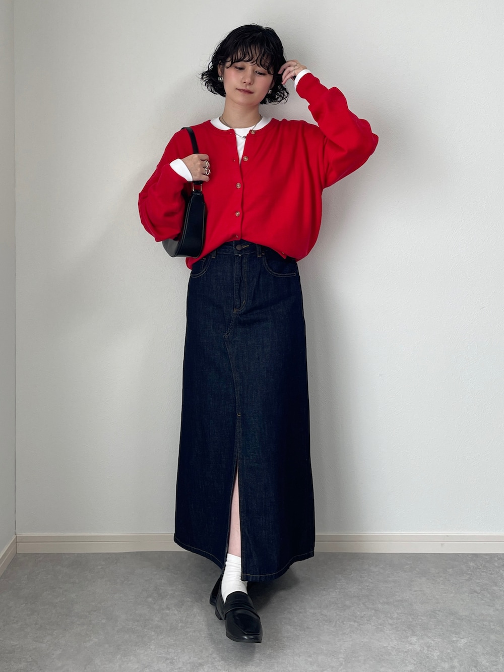 ブラック系のレインシューズ、ブルー系のデニムスカート、レッド系のカーディガン/ボレロを着用したレディースの秋コーディネートの2枚目の写真