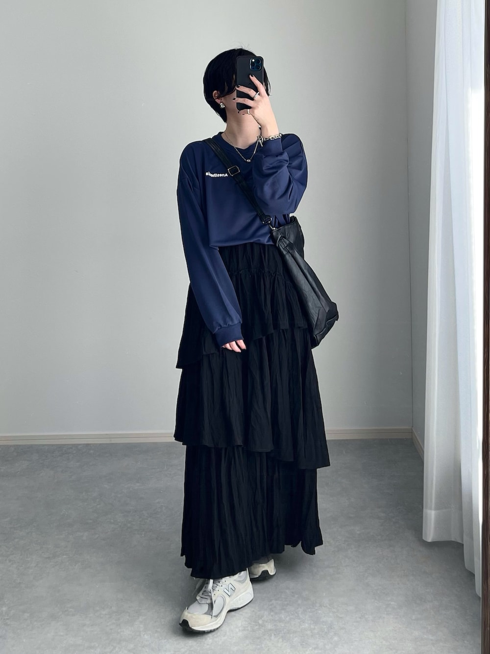 ブラック系のスカート、グレー系のスニーカー、ブラック系のトートバッグを着用したレディースの春コーディネートの2枚目の写真