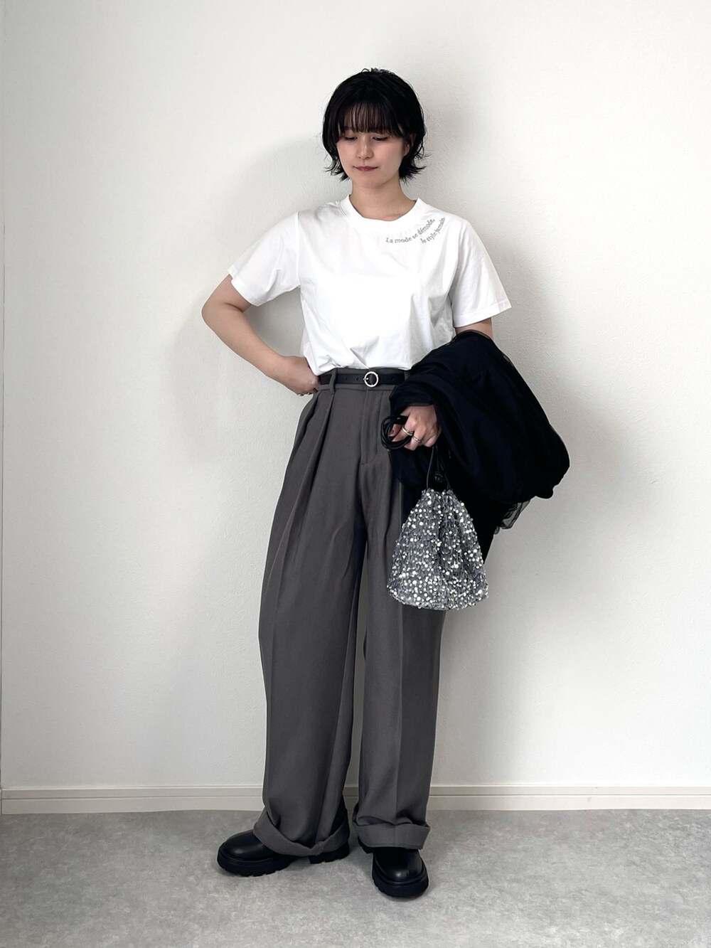 ブラック系のブーツ、グレー系のスラックス、シルバー系のショルダーバッグを着用したレディースの秋コーディネートの2枚目の写真
