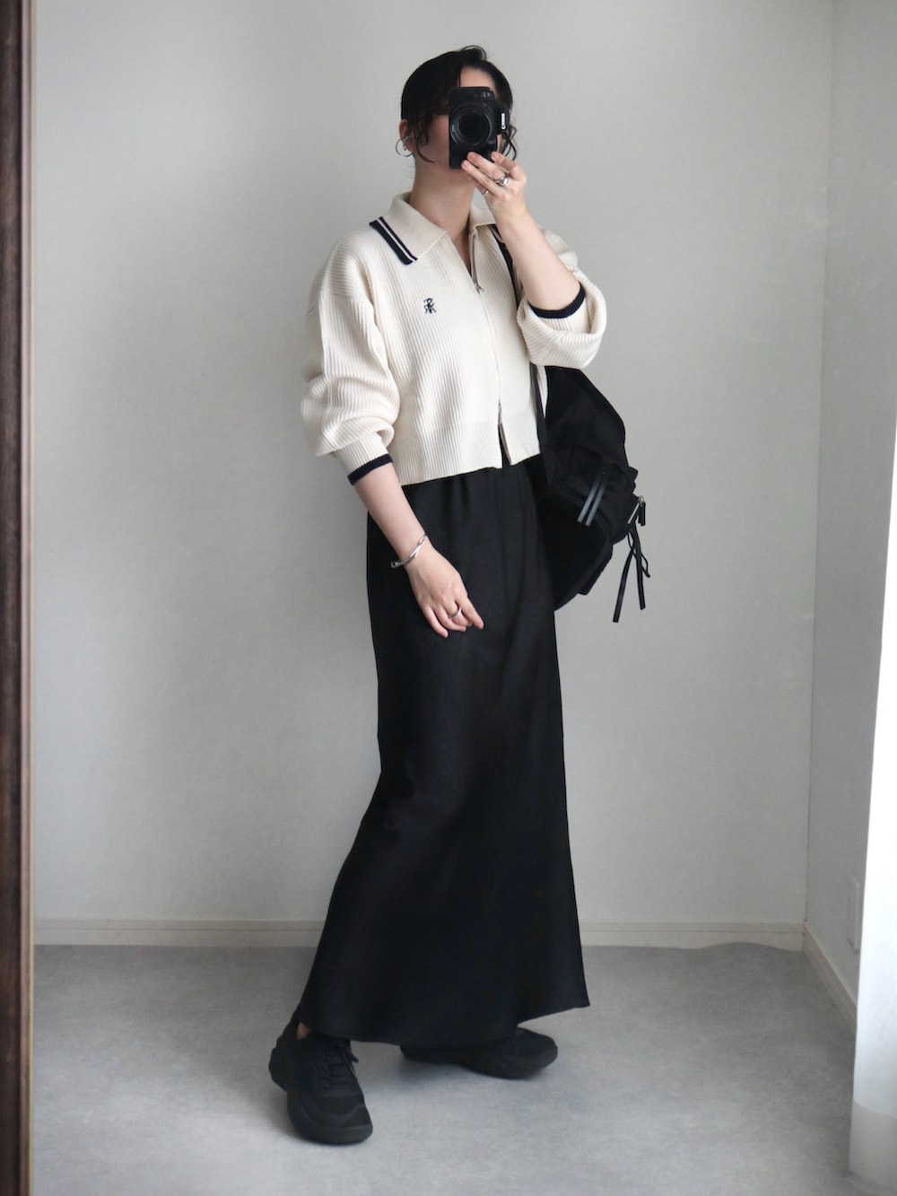 ホワイト系のニット/セーター、ブラック系のスカート、ブラック系のバックパック/リュックを着用したレディースの秋コーディネートの2枚目の写真