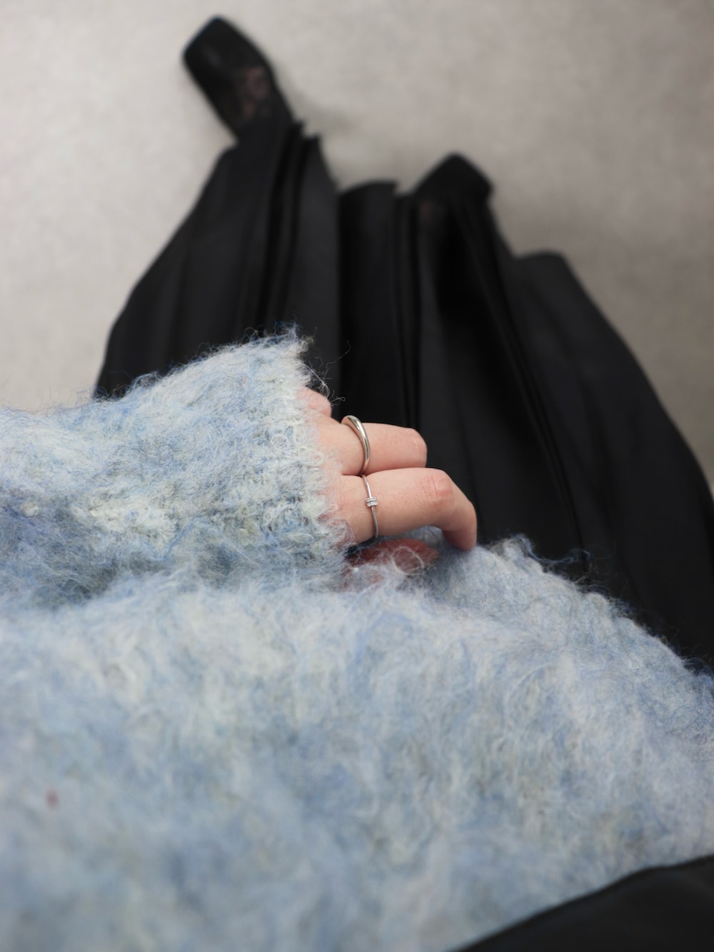 ブルー系のニット/セーター、ブラック系のスカート、ブラック系のショルダーバッグを着用したレディースの春コーディネートの2枚目の写真