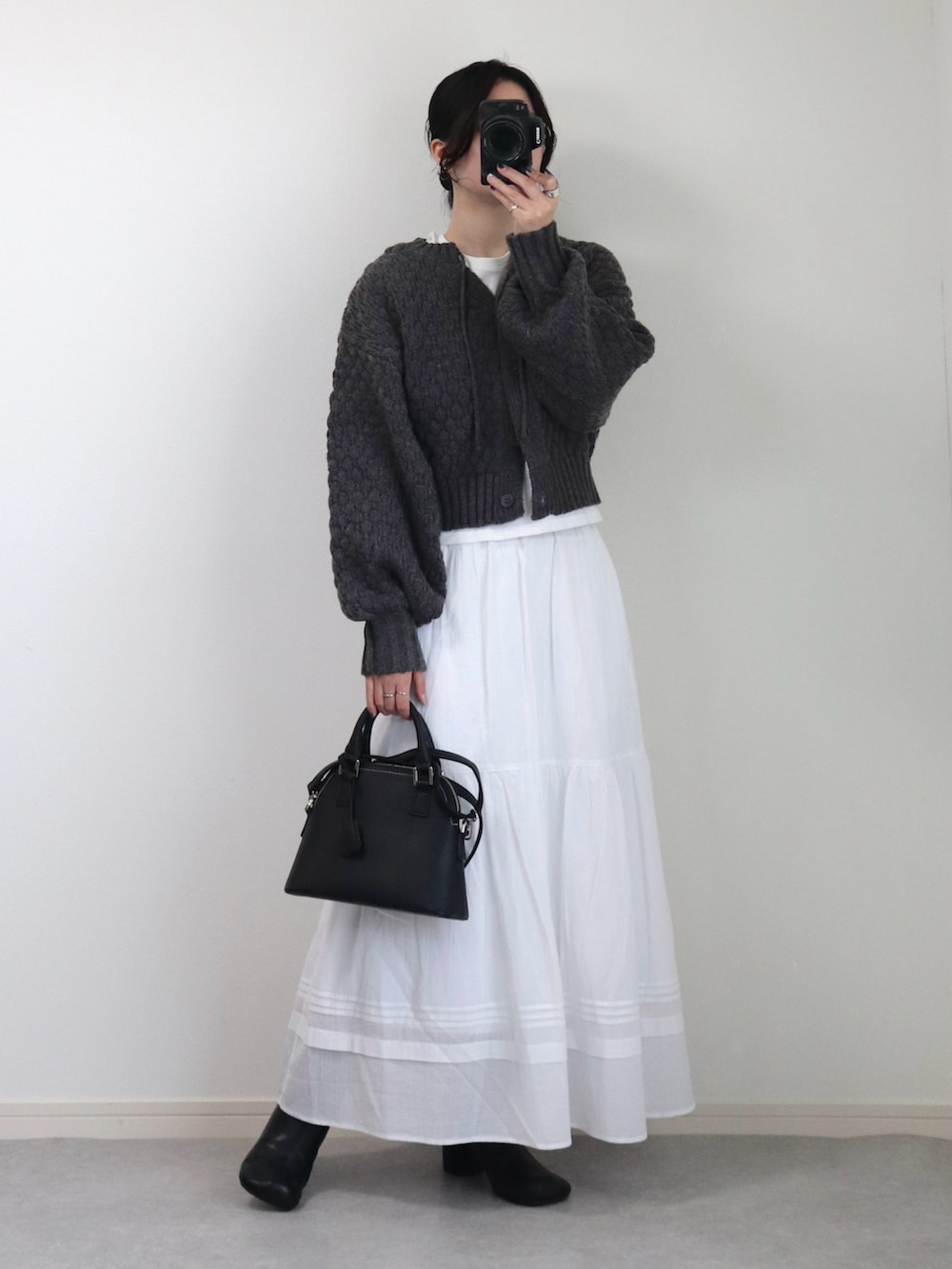 グレー系のニット/セーター、ブラック系のデニムジャケット、ブラック系のブーツを着用したレディースの春コーディネートの2枚目の写真