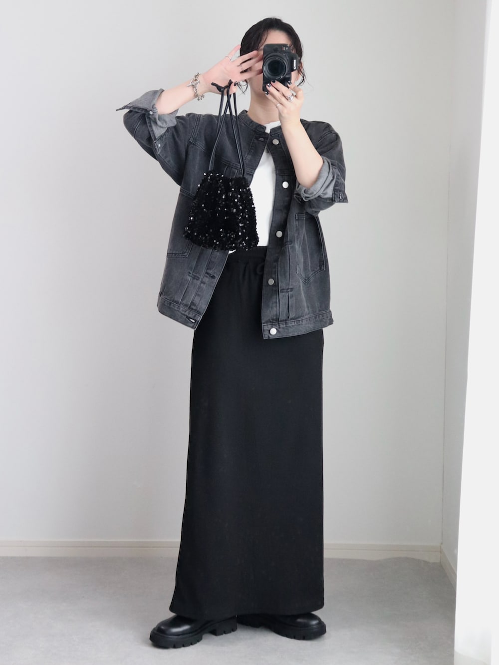 ブラック系のスカート、ブラック系のデニムジャケット、ホワイト系のTシャツ/カットソーを着用したレディースの秋コーディネートの2枚目の写真