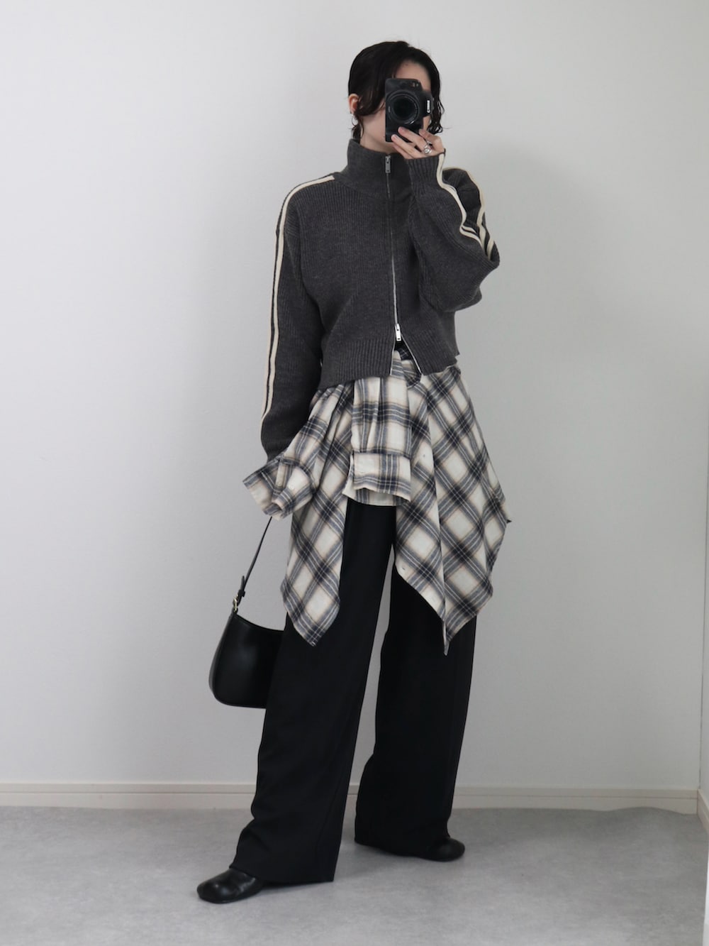 グレー系のニット/セーター、ホワイト系のシャツ/ブラウス、ブラック系のハンドバッグを着用したレディースの秋コーディネートの2枚目の写真