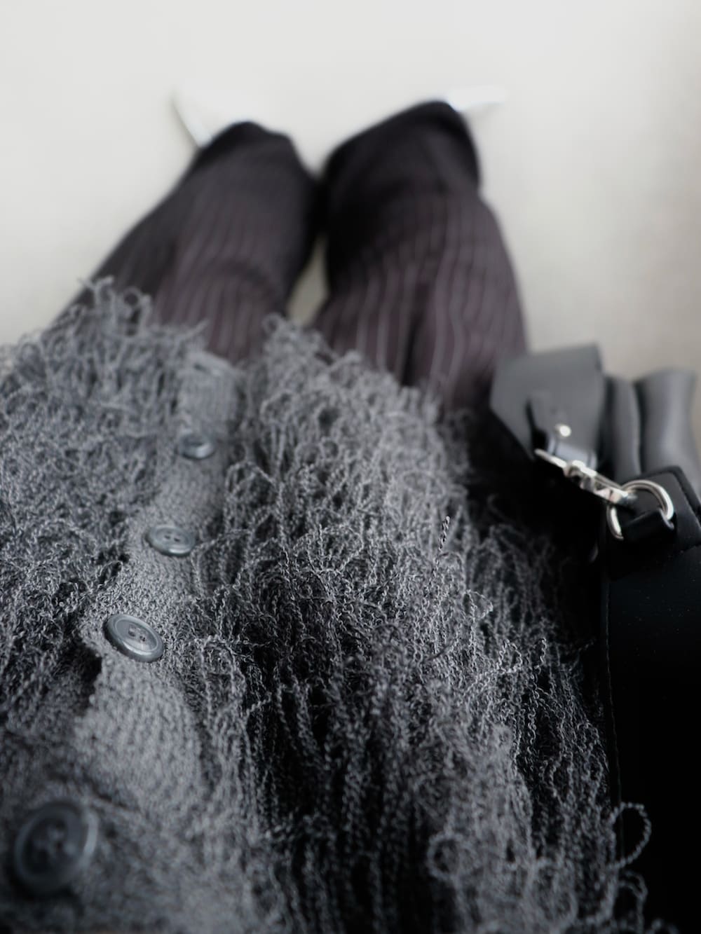 グレー系のベスト、ブラック系のスラックス、ブラック系のショルダーバッグを着用したレディースの秋コーディネートの4枚目の写真