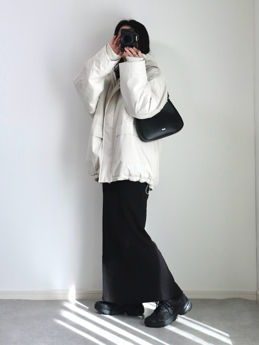 ブラック系のワンピース、ブラック系のハンドバッグ、ブラック系のスニーカーを着用したレディースの冬コーディネートの4枚目の写真