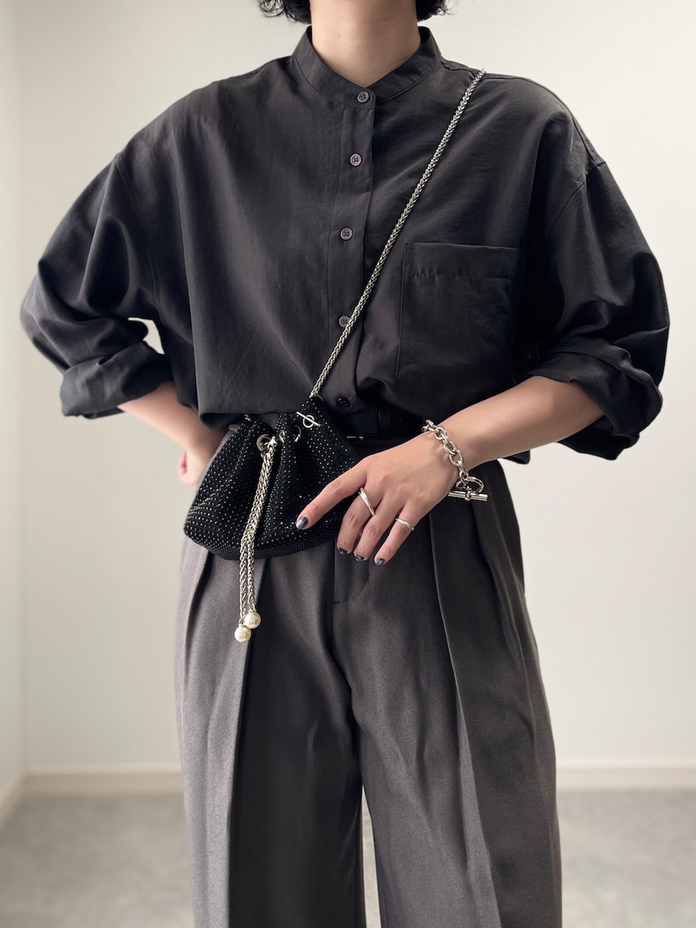 グレー系のスラックス、ブラック系のシャツ/ブラウス、ブラック系のショルダーバッグを着用したレディースの秋コーディネートの2枚目の写真