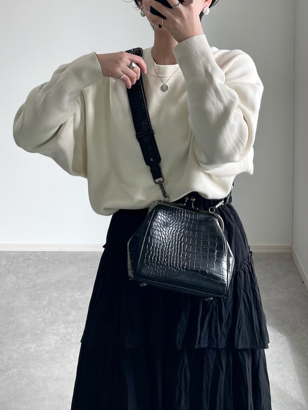 ブラック系のスカート、ホワイト系のニット/セーター、ブラック系のバッグを着用したレディースの冬コーディネートの2枚目の写真