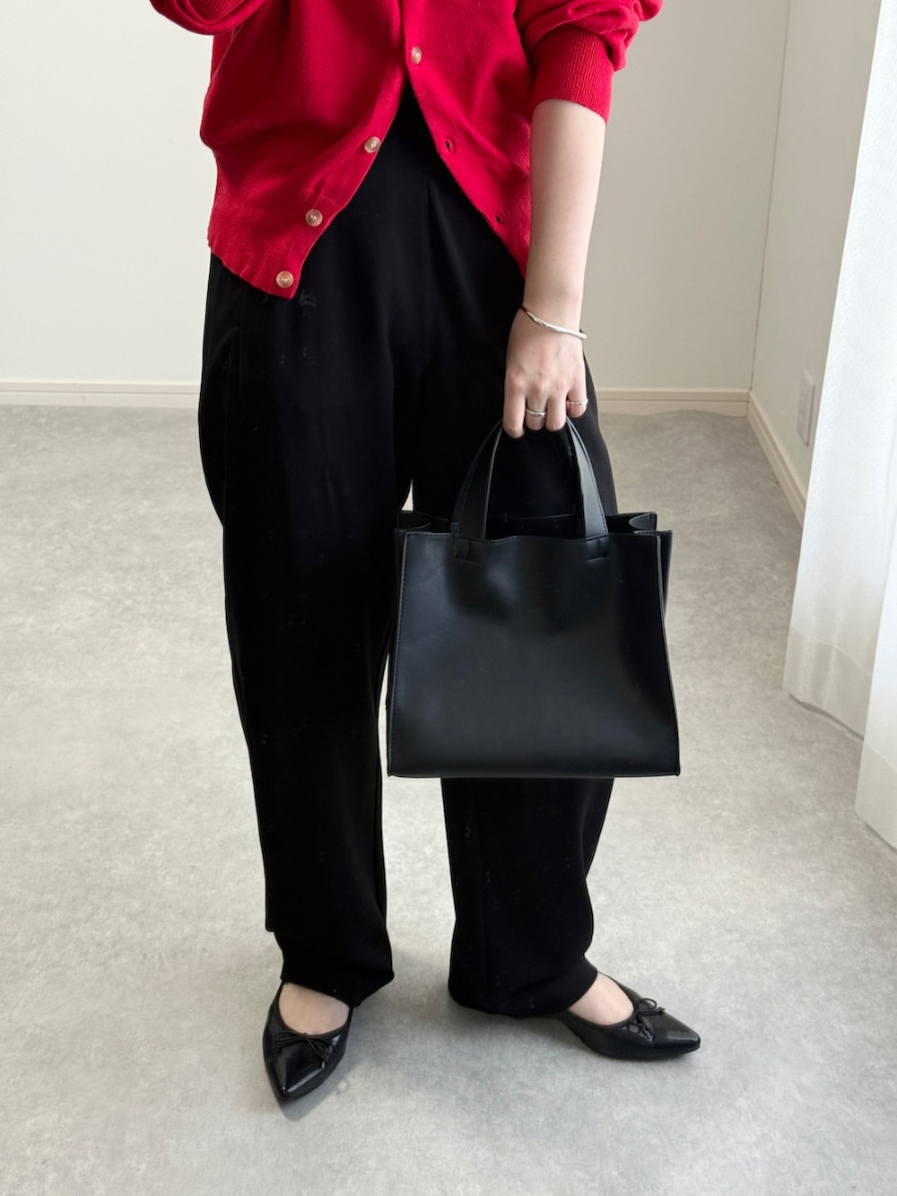 ブラック系のトートバッグ、レッド系のカーディガン/ボレロ、ブラック系のその他パンツを着用したレディースの秋コーディネートの2枚目の写真