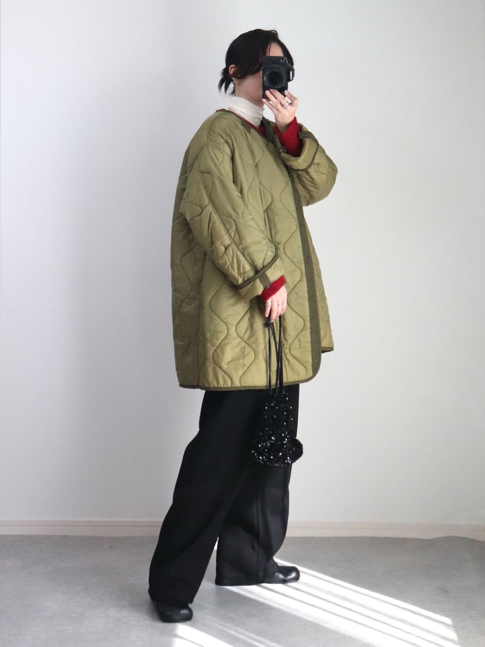 ブラック系のスウェットパンツ、ブラック系のブーツ、グリーン系のモッズコートを着用したレディースの秋コーディネートの4枚目の写真