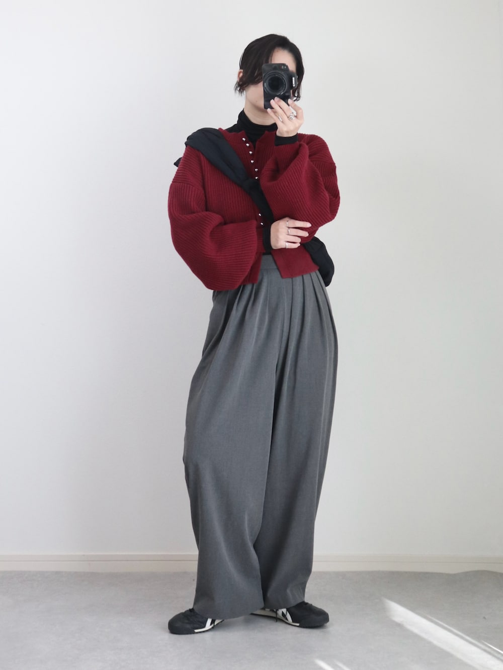 レッド系のカーディガン/ボレロ、グレー系のスラックス、ブラック系のニット/セーターを着用したレディースの秋コーディネートの2枚目の写真
